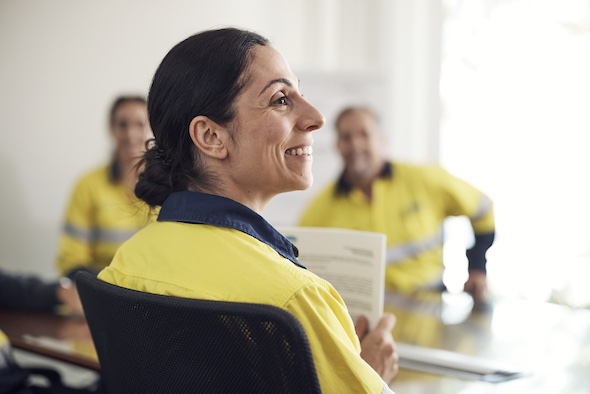 A smiling female employee sitting in a meeting room with others