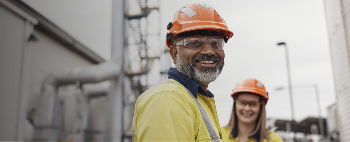 Two BlueScope employees at manufacturing plant looking to camera