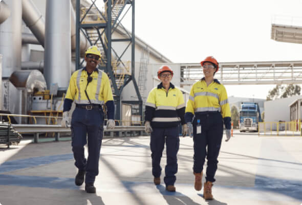 Three BlueScope employees outside manufacturing plant walking to camera
