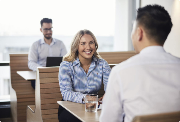 Three People sat in booths. Two in conversation 