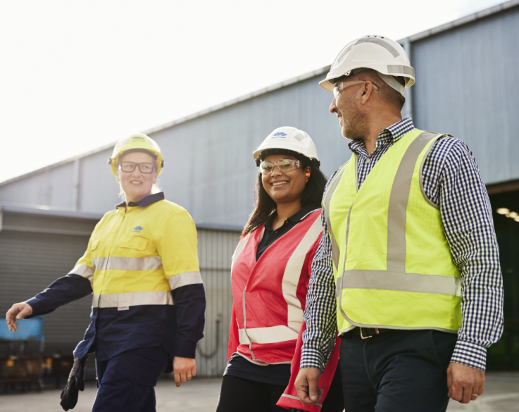 Three employees in high-visibility clothing walk away from a loading bay