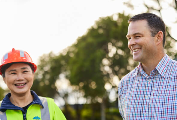 BlueScope employee and man in check shirt stand smiling outside