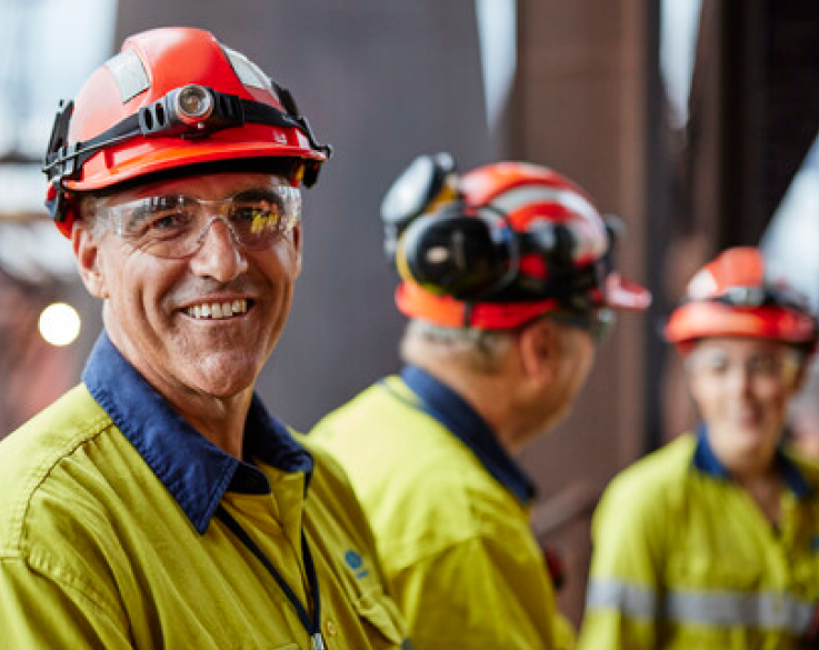 Three Bluescope employees in full PPE, one looks into the camera