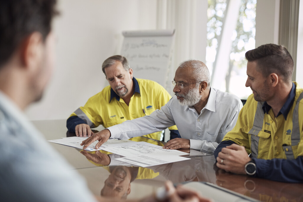 Three BlueScope employees examining plans in a board room