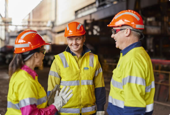 Friendly conversation between three employees in high-visibility clothing