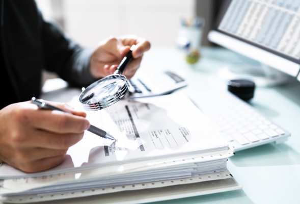 Employee takes magnifying glass to paper work 