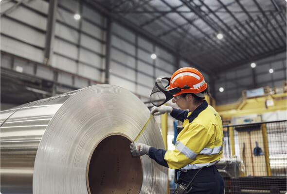 BlueScope employee in high visibility uniform with tape measure, measuring width of steel coil