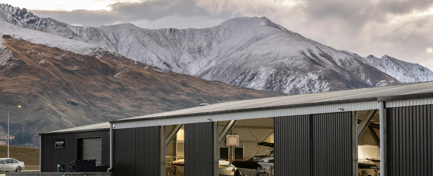 Marine hanger that features COLORSTEEL DRIDEX® Steel Roof & Wall Cladding from New Zealand Steel set with a mountain scape backdrop.