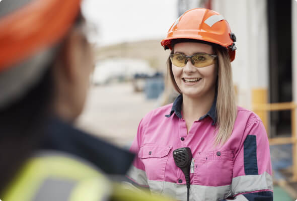 Female BlueScope employee in pink high-visibility jacket talking with a colleague