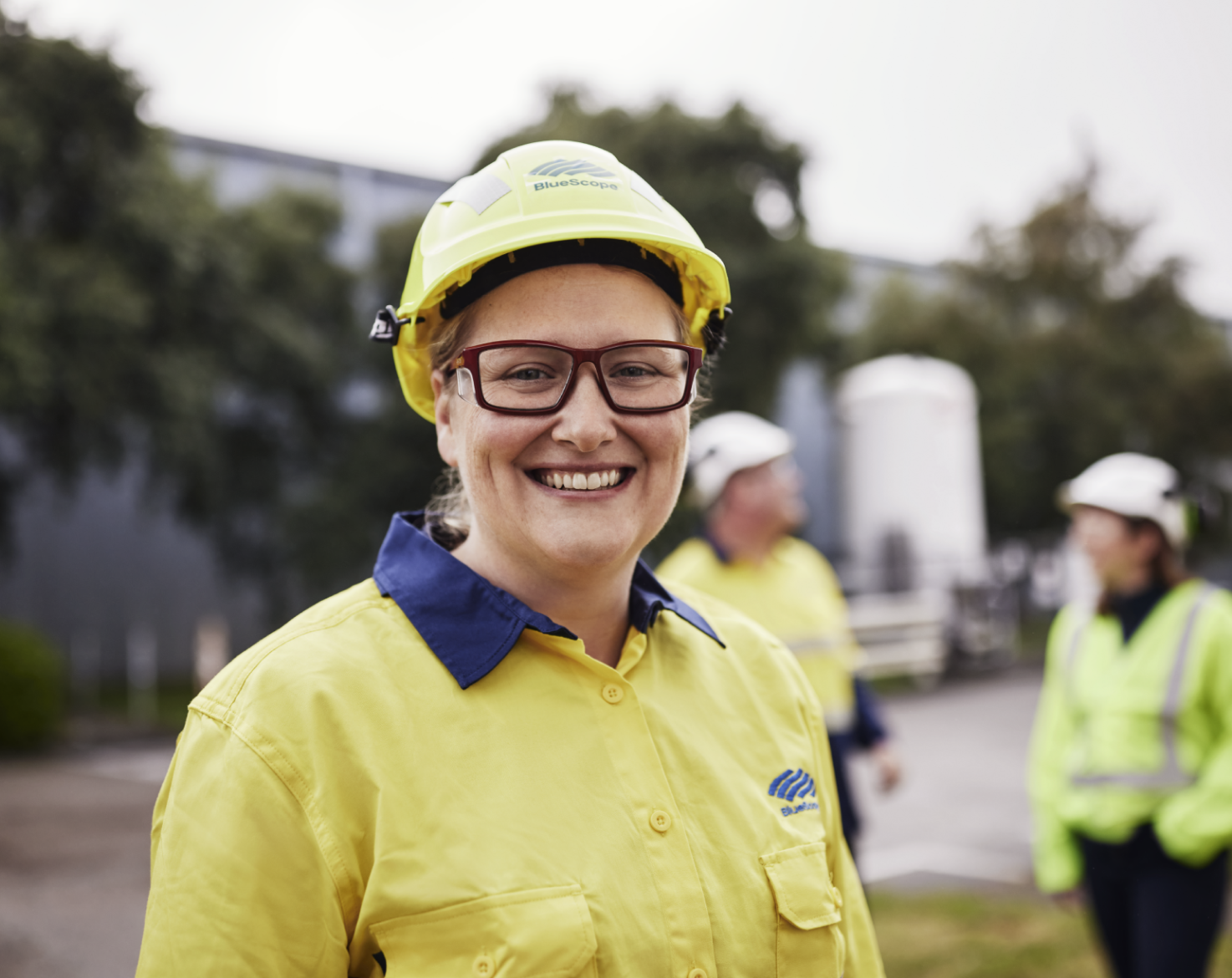 Smiling female BlueScope employee in yellow high-visibility clothing