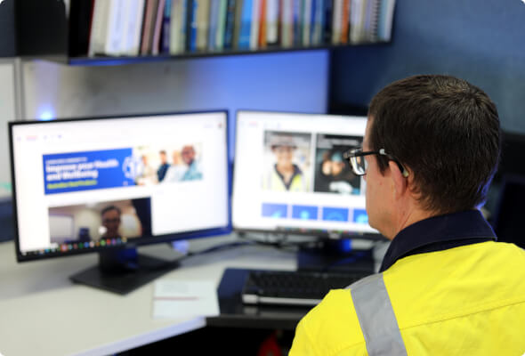 BlueScope employee in high-visibility jacket working on a computer.