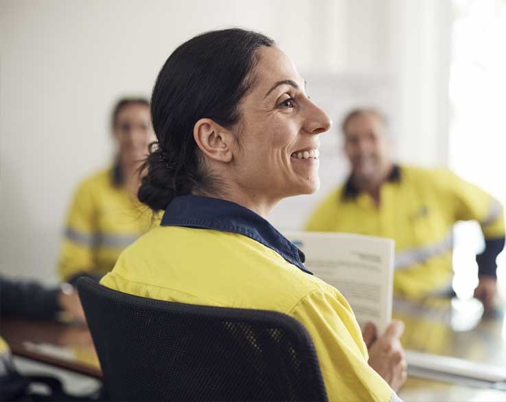 A smiling female employee sitting in a meeting room with others